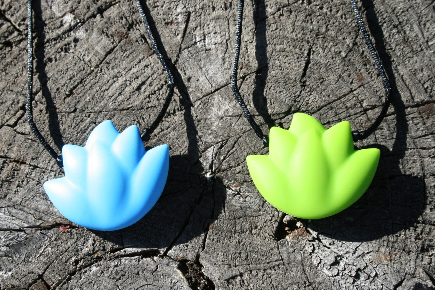 Sensory Necklace with Silicone Lotus Pendant - Available in 2 colors: Sky blue or Lime green -This pendant and is made from food-grade silicone, strung on a nylon cord, and finished off with a plastic clasp designed to pop open when pulled (Jewelry on wooden background)
