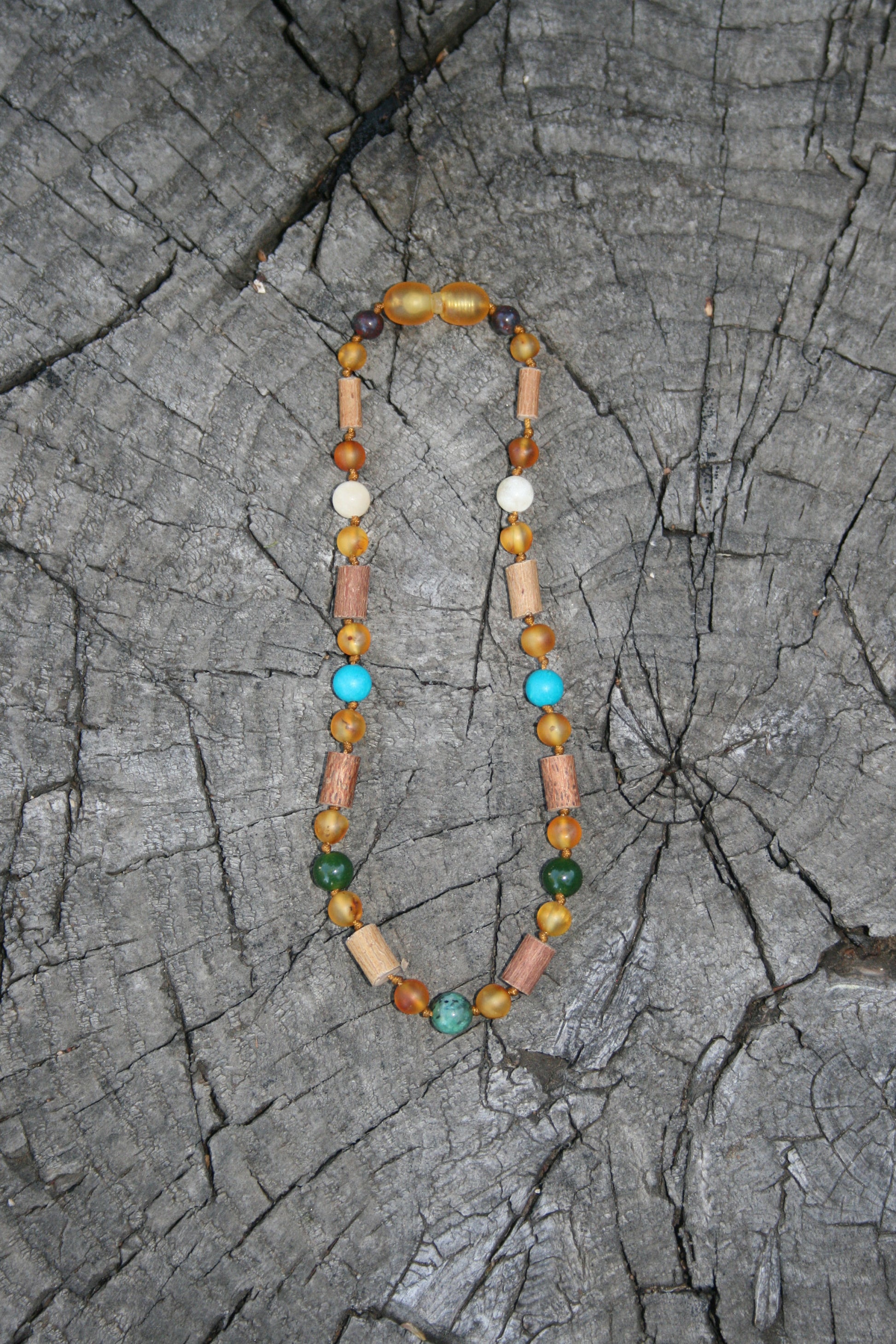 Picture is of hazelwood, honey colored amber, and reflux stones. (Jewelry on wooden background)