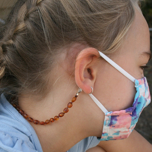 Picture of blonde youth age girl with a mask chain/ glasses chain, The lobster claw  pair of glasses or sunglasses with the adjustable soft rubber clasp. Wearing Baltic amber , listing is for any length Mask Chain/ Glasses Chain and made with unpolished Baltic amber beads and nickel free, lead free, silver plated lobster clasps.