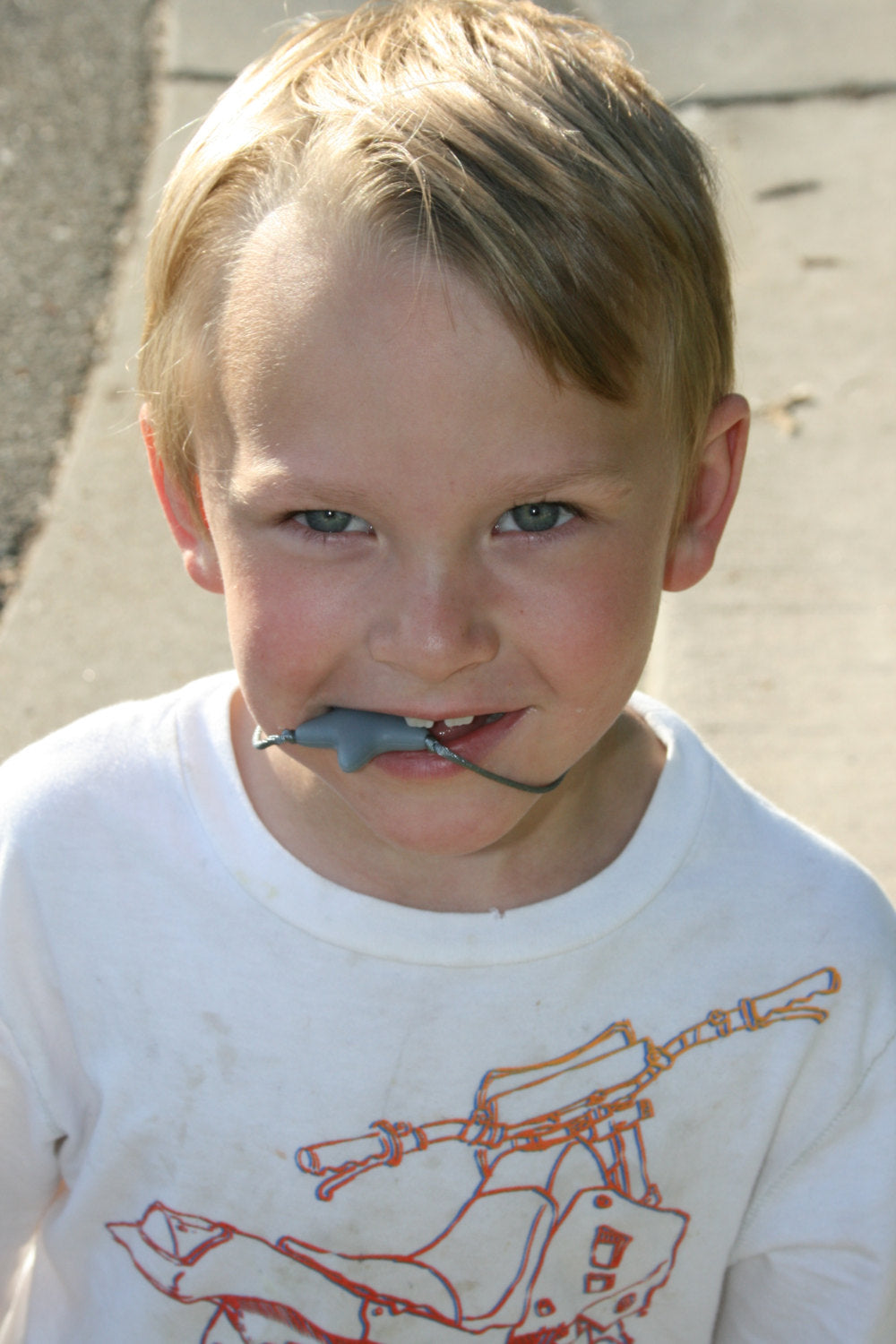 Model wearing and usingSensory Necklace Chewable for Children with Star Pendant available in 3 colors: gray, hot pink, and aqua blue. Measures approximately 18", but can be made longer if needed. This pendant and is made from food-grade silicone, strung on a nylon cord, and finished off with a plastic clasp designed to pop open when pulled really hard. (Jewelry on wooden background)