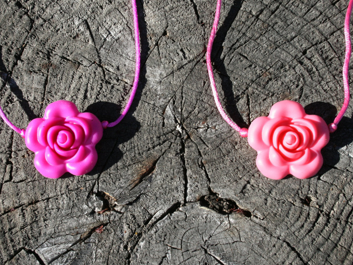 Sensory Necklace with Silicone Rose Pendant- Available in 2 colors: Hot Pink or Light Pink -This pendant and is made from food-grade silicone, strung on a nylon cord, and finished off with a plastic clasp designed to pop open when pulled (Jewelry on wooden background)  