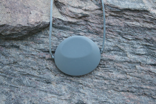 Picture of Chewable Sensory Necklace for Children with Large Oval Pendant and is made from food-grade silicone, strung on a nylon cord, and finished off with a plastic clasp. (Necklace on rock background)